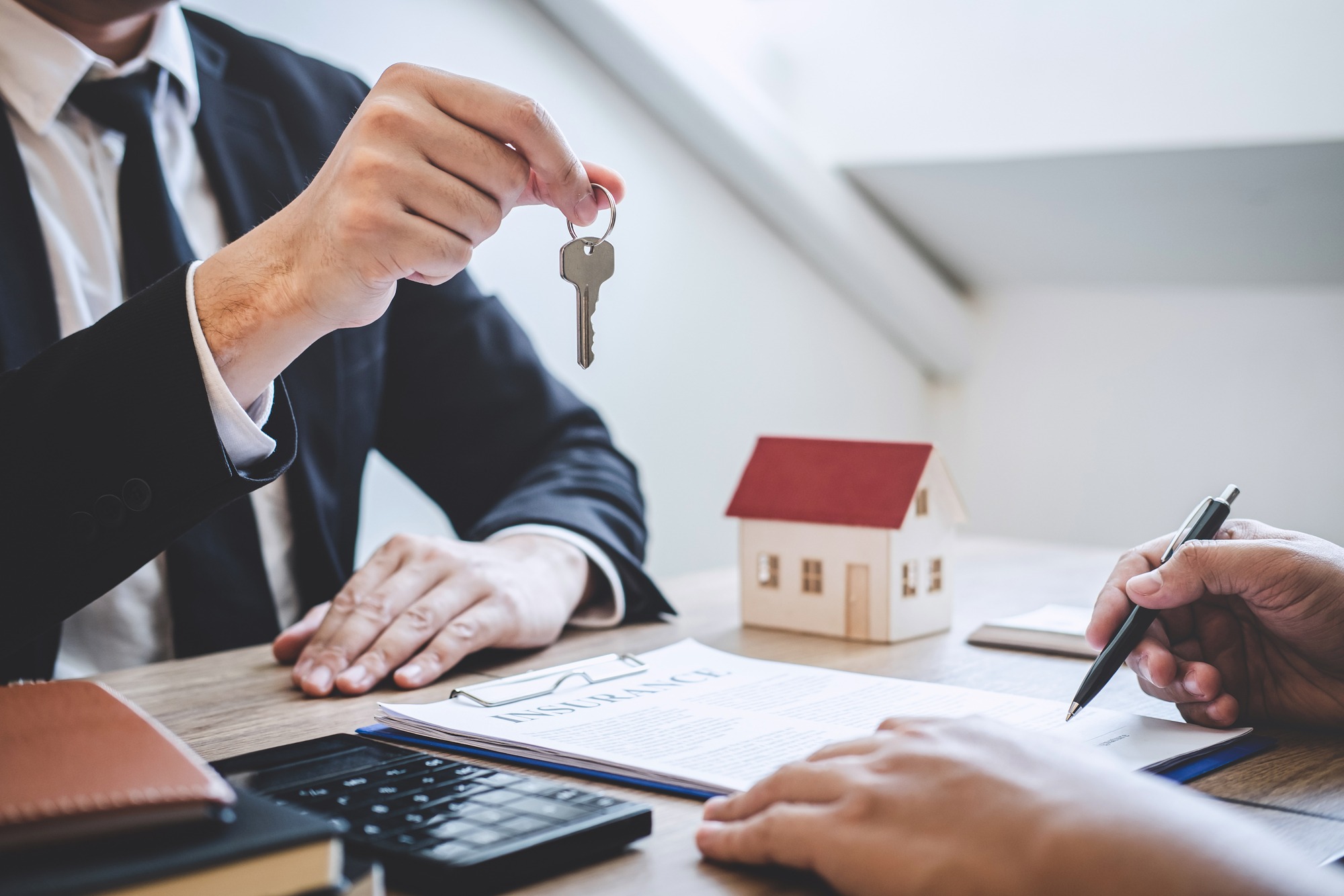 Estate agent giving house keys to client after signing agreement